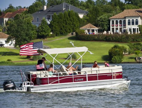 Macon, GA, 07/04/2016:
A pontoon boat flying the American Flag passes by Sandy Beach and Sparks Over the Park Independence Day Celebration at Lake Tobesofkee.