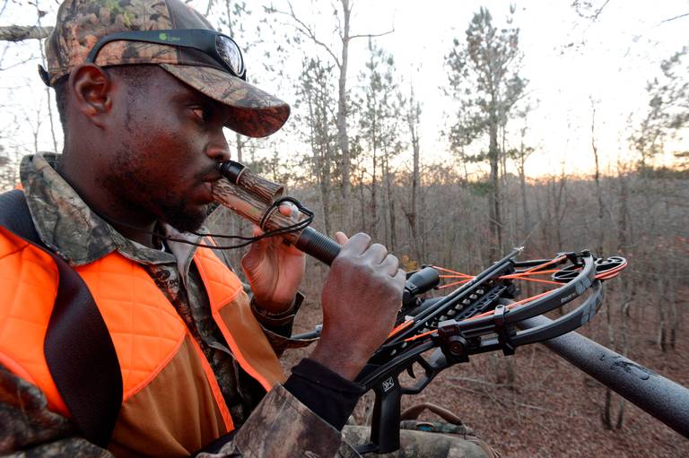 Edwin Pierre-Lewis, a native of Haiti who attends graduate school at the University of Georgia, uses a buck call as he hunts deer west of Athens. He learned to hunt as part of the Field to Fork program and has become a mentor, now teaching others how to hunt.