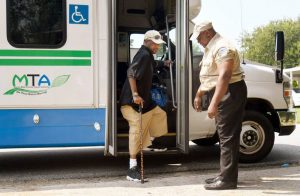 Macon, GA, 08/14/2018: Macon Transit Authority driver Charlie Huff watches over as Donald Wade exits a paratransit bus at his home in West Bibb County August 14, 2018, after receiving dialysis at a center in downtown Macon.