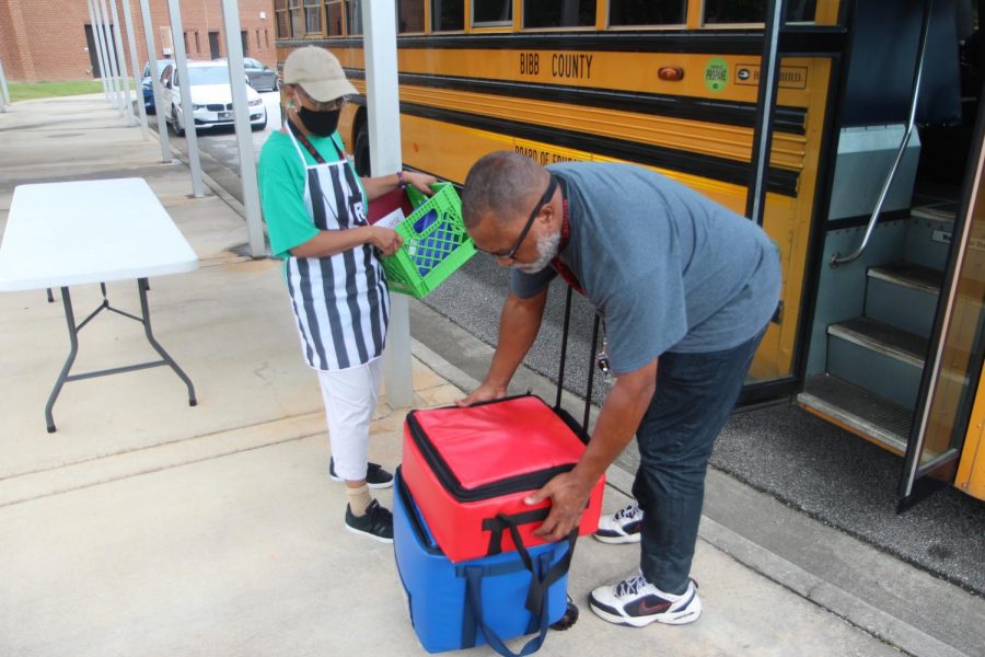 Bus driver Michael Huff and cashier Barbara Blair load meals onto a school bus at Burdell-Hunt Magnet Elementary School.