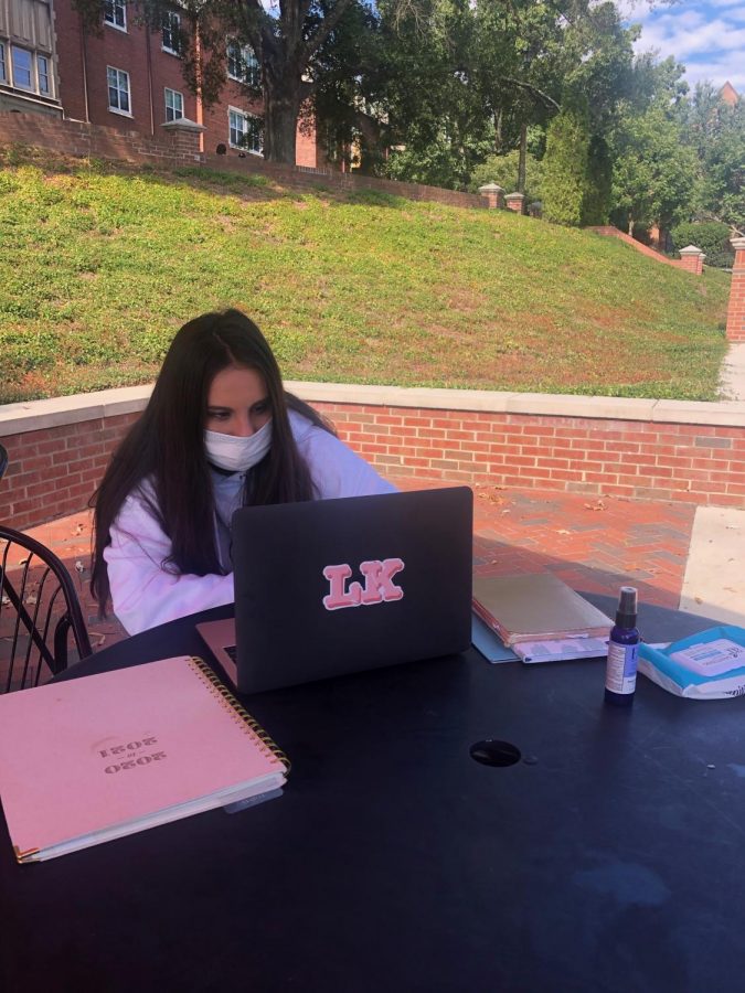 Mercer International student, Lucia Guiterrez, sits outside on campus working on an assignment.
