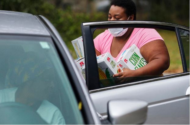 Volunteer Kenya Hampton loads groceries in the back of a recipients car. According to the group Feeding American, just under half of the people accessing food aid during the COVID-19 recession are doing so for the first time in their lives.
