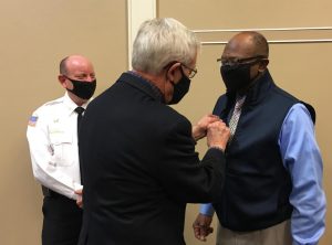 Retired Macon-Bibb fire chief Marvin Riggins, right, receives an honorary Kiwanis Club pin from Bob McDuffie as acting Chief Shane Edwards looks on. 