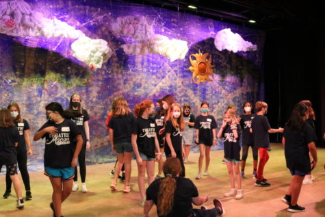 A group of students standing on stage as they practice sound and lighting design at Theatre Macon Academy summer camp.