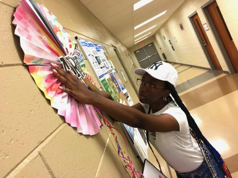 Serenity Wright hangs her artwork and handmade decorations Monday in the hall of the Bloomfield Recreation Center at 1931 Rocky Creek Road.
