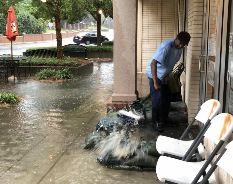 Francars restaurant owner Carl Fambro sweeps flash flood water from the front of his business in September. 