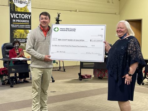 Macon-Bibb County Industrial Authority Executive Director Stephen Adams presents Bibb County Schools Chief Finance Officer Sharon Roberts with a check for $1.4 million at the Dec. 16, 2021, meeting. The money is a reimbursement for property tax abatements the authority uses as an incentive to draw businesses to Macon.