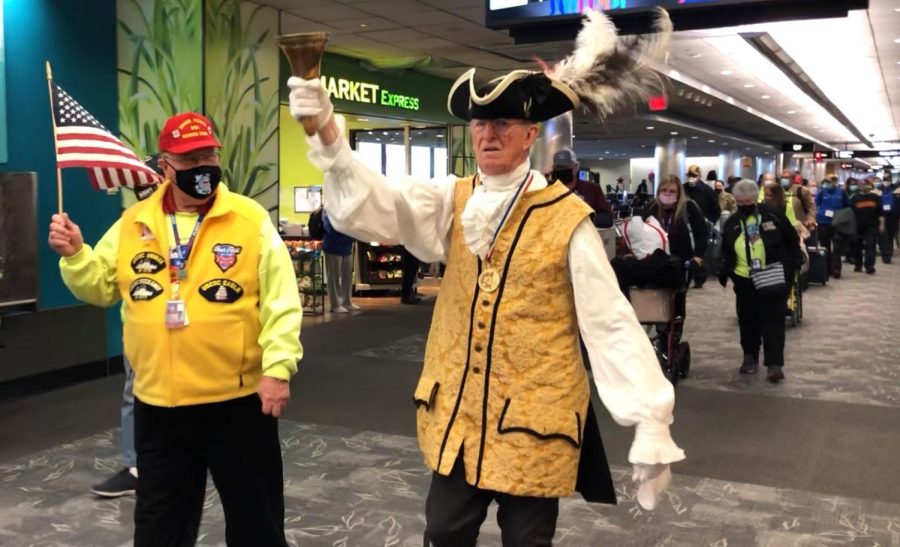 The official town crier of Annapolis, right, leads war veterans from the Middle Georgia Honor Flight through the Baltimore-Washington International Airport on March 12. 