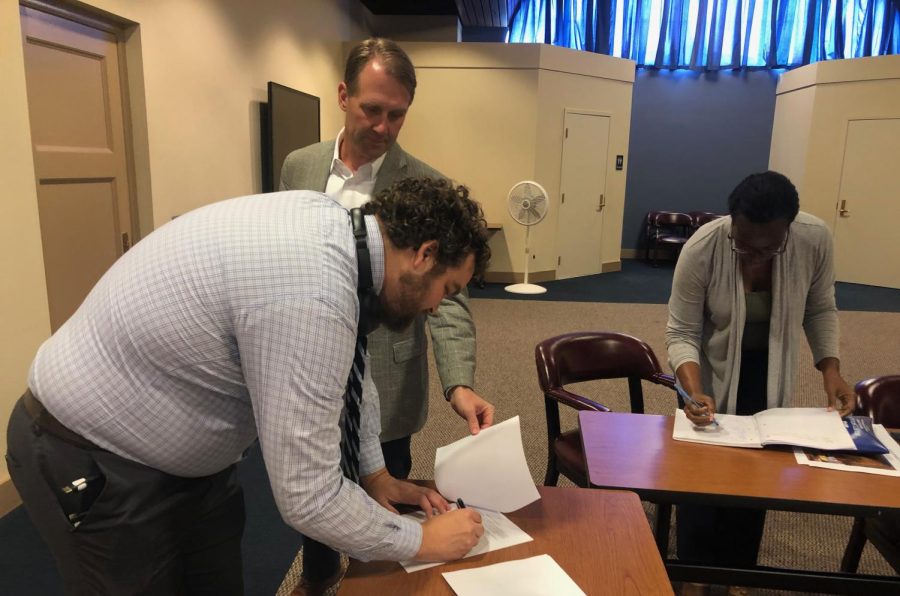 Macon-Bibb County Urban Development Authority Executive Director Alex Morrison signs the resolution Thursday to provide up to $44 million in bonds for the renovation of Macon Mall and new amphitheater. 