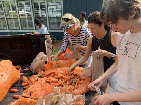 Louis McMickle (right), Kara McMickle and Janie Wilhoit add carrots to bags of food being distributed across Bibb County. Volunteers with The Mentors Project met June 30 to pack and deliver food.