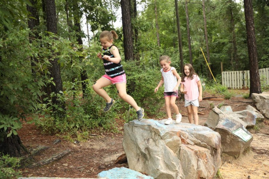 Trinity Woods campers take turns jumping off a rock.