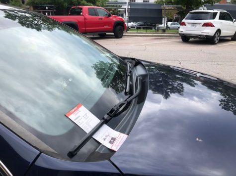 A fresh parking ticket sits under the windshield wiper of a Lexus recently caught overdue parking on Poplar Street. At least one other faded, unpaid ticket was on the dashboard of the car. 
