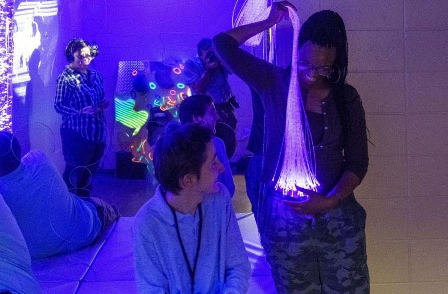 Central High School senior Gabe Deegan watches assistant teacher and parapro Madelynn Washington hold a stream of optical fiber lights in the schools new sensory room on Oct. 25, 2022.