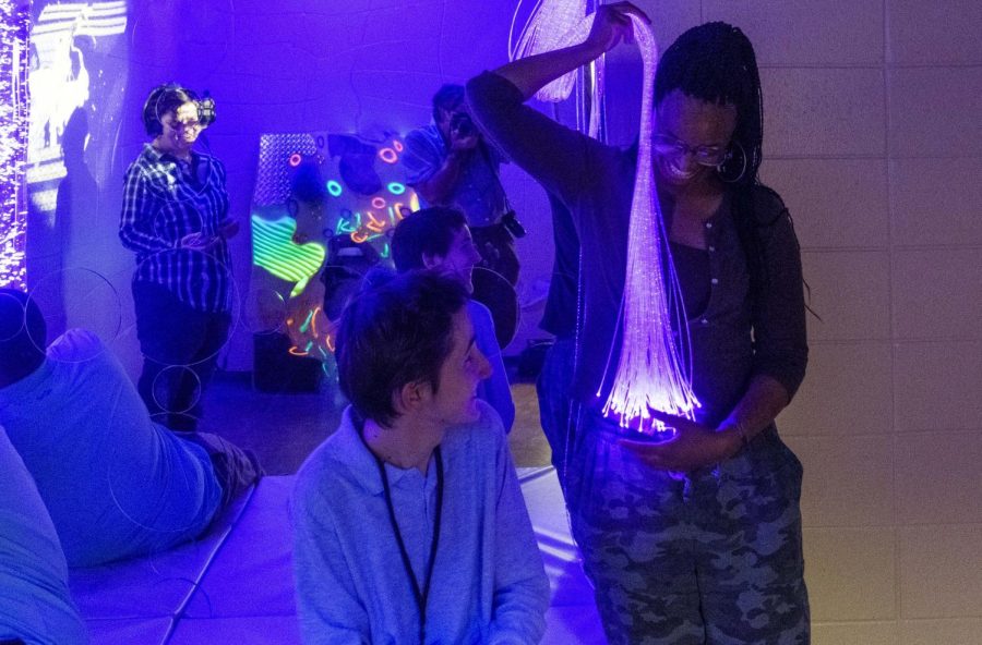 Central High School senior Gabe Deegan watches assistant teacher and parapro Madelynn Washington hold a stream of optical fiber lights in the school's new sensory room on Oct. 25, 2022.