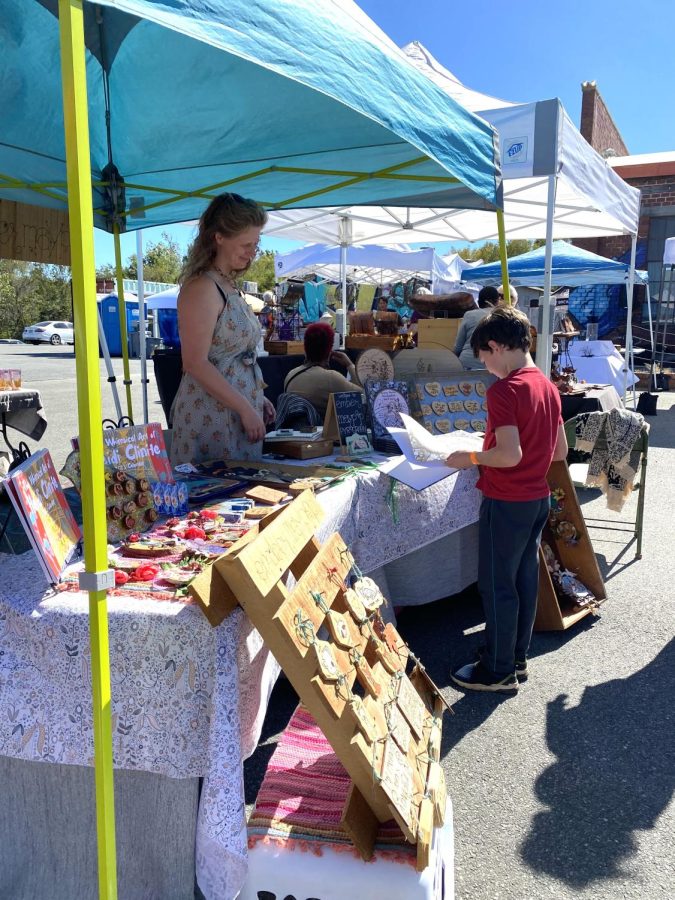 Art vendor at the All Hands Art Festival at the Triangle Arts Macon on Oct. 1, 2022 interacts with a young customer.