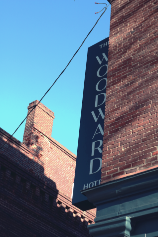 The Woodward Hotel dark blue sign warmly greets patrons on the corner of Second and Mulberry Street.