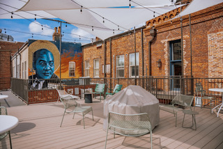 The rooftop patio provides an atmosphere of connection between the present and the past. The mural in the background gives homage to Southern literary legends like John O. Killens, an author and civil rights activist. Courtesy of The Moonhanger Group.