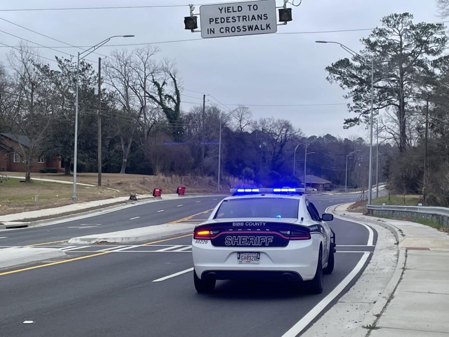 A Bibb County sheriff deputys car with blue lights activated near a pedestrian crosswalk on Jeffersonville Road in Macon.