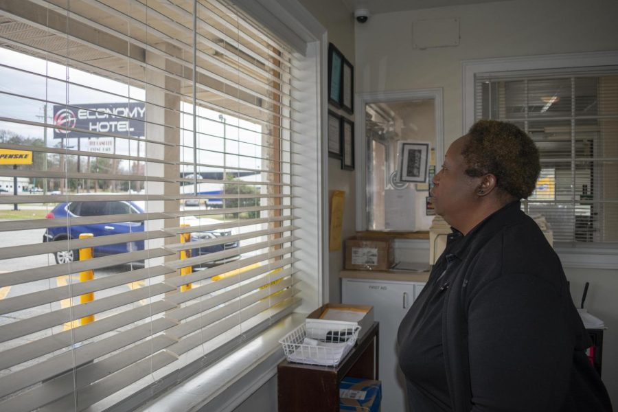 Imogene Patterson peers through the blinds behind the check-in desk at Economy Hotel on Pio Nono. She said she sometimes holds her breath watching some of the hotel guests trying to cross the five lanes of Pio Nono Avenue to get to the Circle K convenience store.