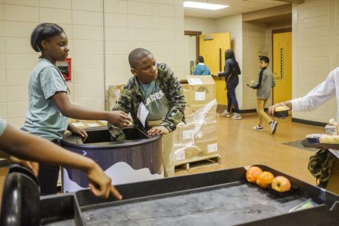 Ballard Hudson Middle School students Jalexia Maloy, left, and Jayden Parker, center, collect food during their lunch period in their roles as volunteer workers in the Helping Hands Ending Hunger program. Grant Blankenship/GPB News
