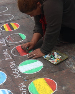 International woman does chalk art of country flags.