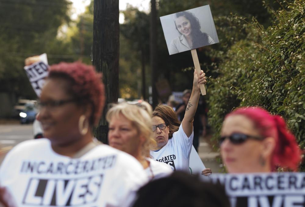 Protesters were outside the Georgia Governors Mansion on Oct. 3, 2023 to bring attention to violence and other concerns in Georgias prisons. One protester carries a photo of Stephanie Widener, who died of sepsis in Georgia Department of Corrections custody.