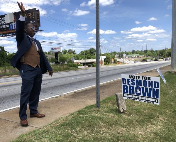 Macon Water Authority incumbent Desmond Brown waves from the sidewalk at Macon Mall where early voting is underway at the Macon-Bibb County Board of Elections. Brown said the malls sign prohibition infringes on his ability to campaign. 