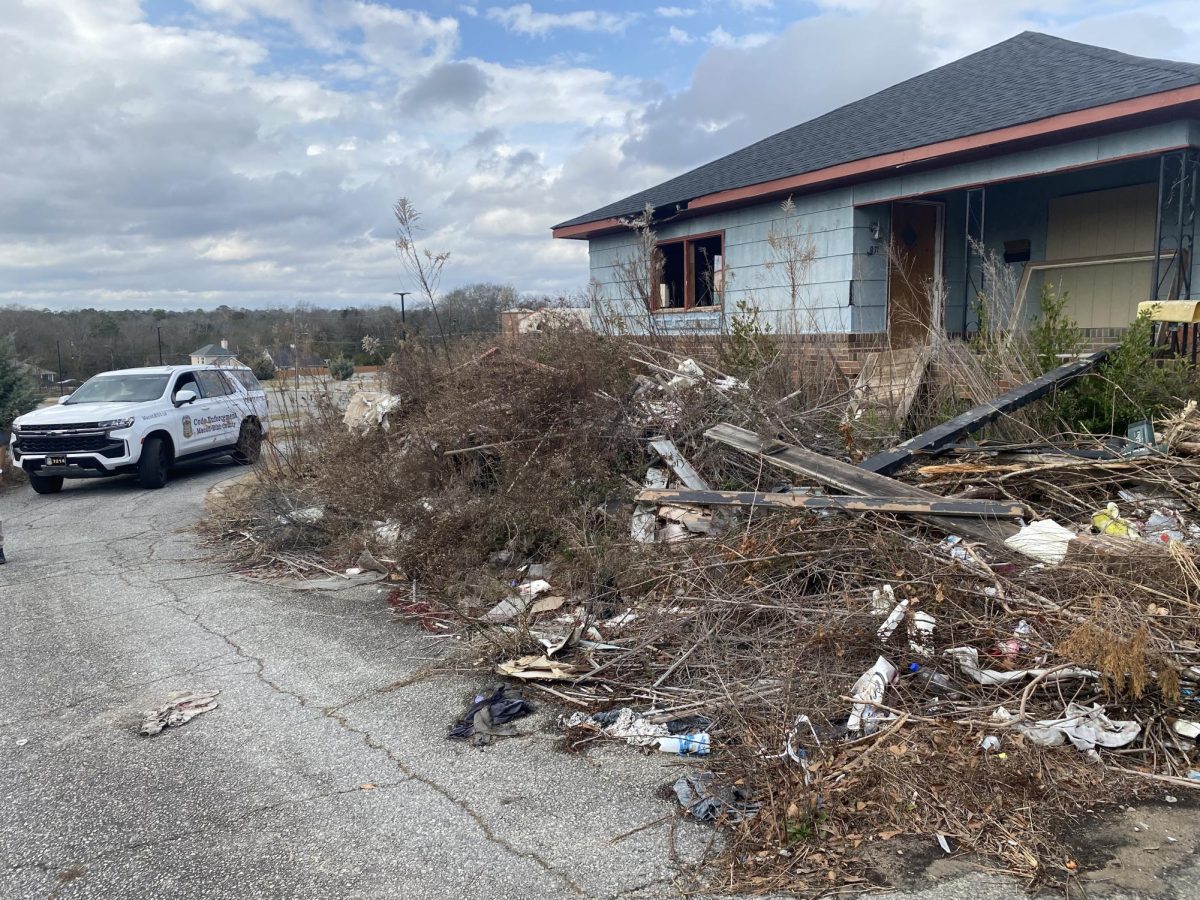 A blight-affected Macon property sits alongside illegal dumping as a Code Enforcement officer patrols the area in January 2024.