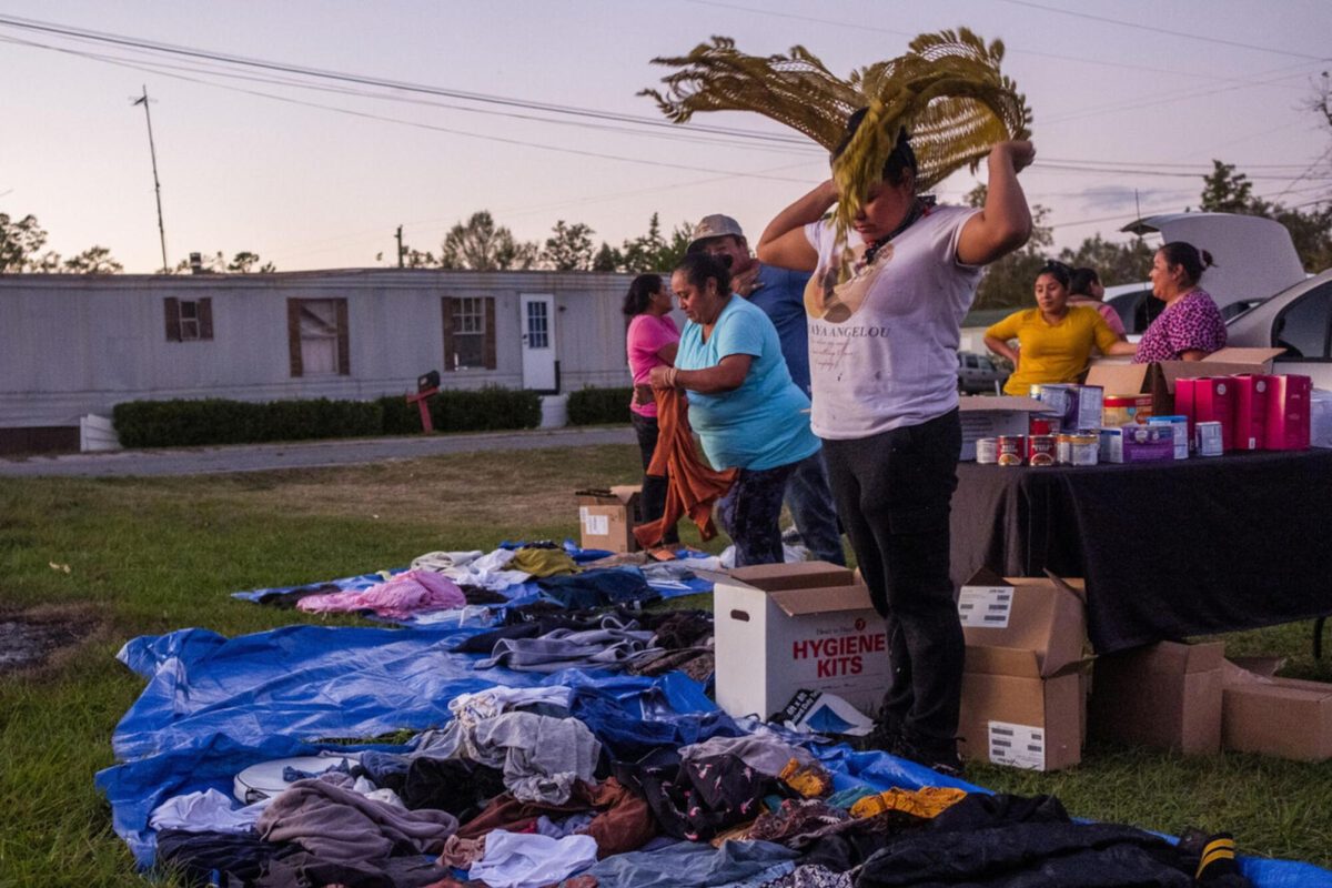 Nimsy Gomez tries on a knitted shawl while going through clothes donated by United Farm Workers to a community of Latino laborers still recovering from Hurricane Helene east of Tifton. People were given the basics: food, hygiene products, baby formula and, with winter coming, warm clothes to help them endure the cold that will seep into trailer homes.