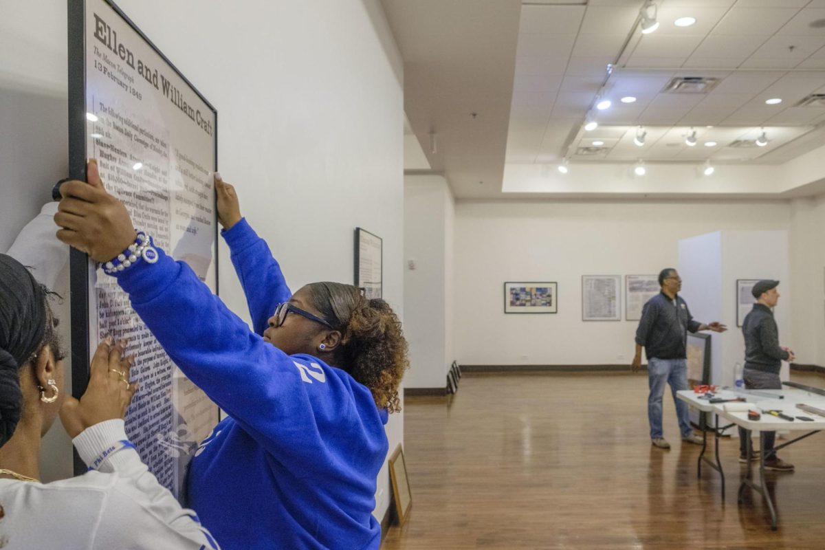 Mercer University sophomore Taylor Boyd mounts a piece of the Freedom Seekers exhibit at the Tubman African American Museum in Macon in 2025. The exhibit features so-called “runaway slave ads” researched by students like Boyd. “They had everyday problems just like us,” Boyd said. “Reading their stories and reading that they were running away to families or they had lovers — that really just exemplified the importance of why we need to showcase this.”