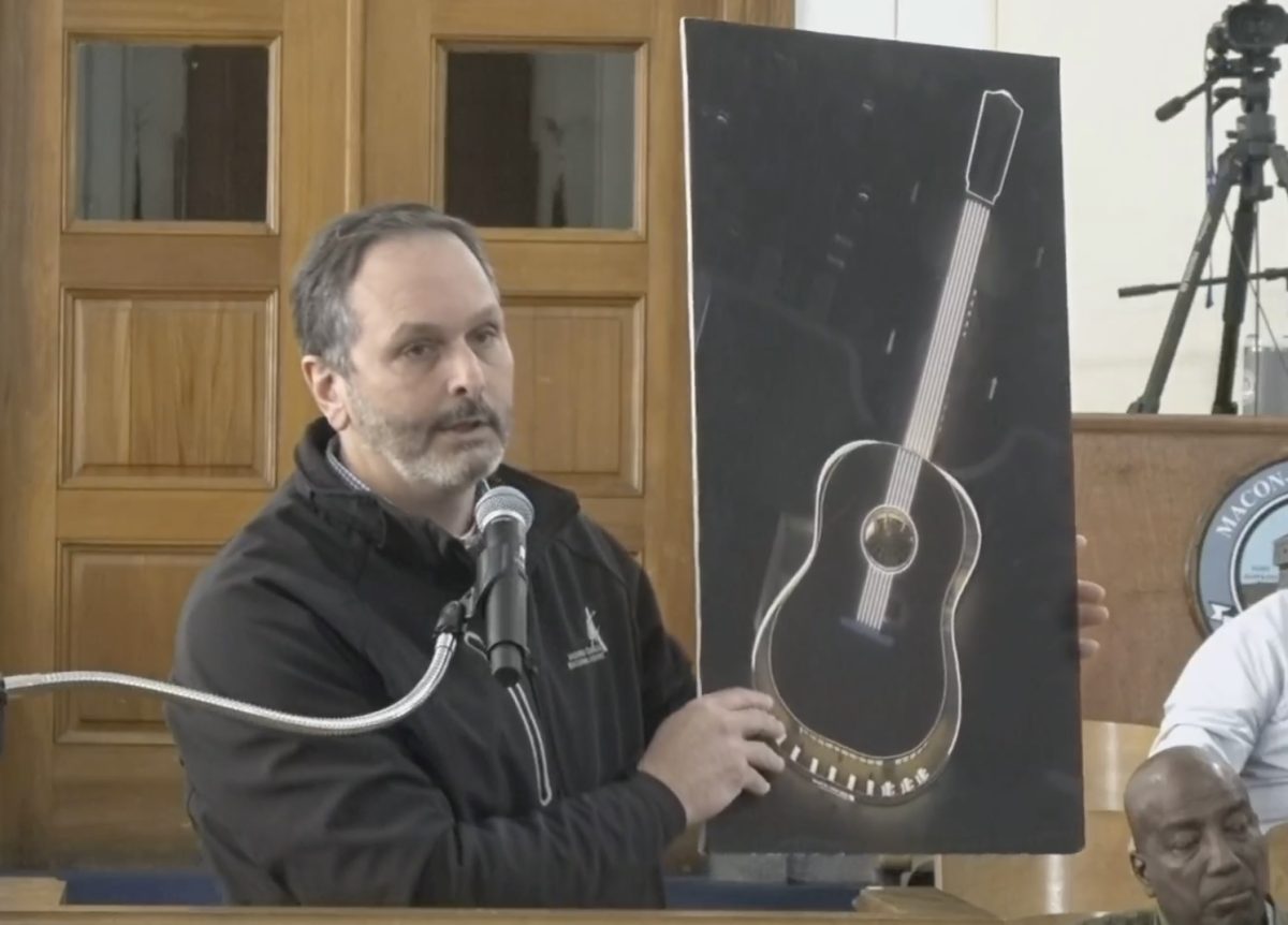 Macon-Bibb County Aviation Director Doug Faour holds up an image of the planned guitar-shaped High Note Aviation executive terminal at Middle Georgia Regional Airport that will be lit up at night.