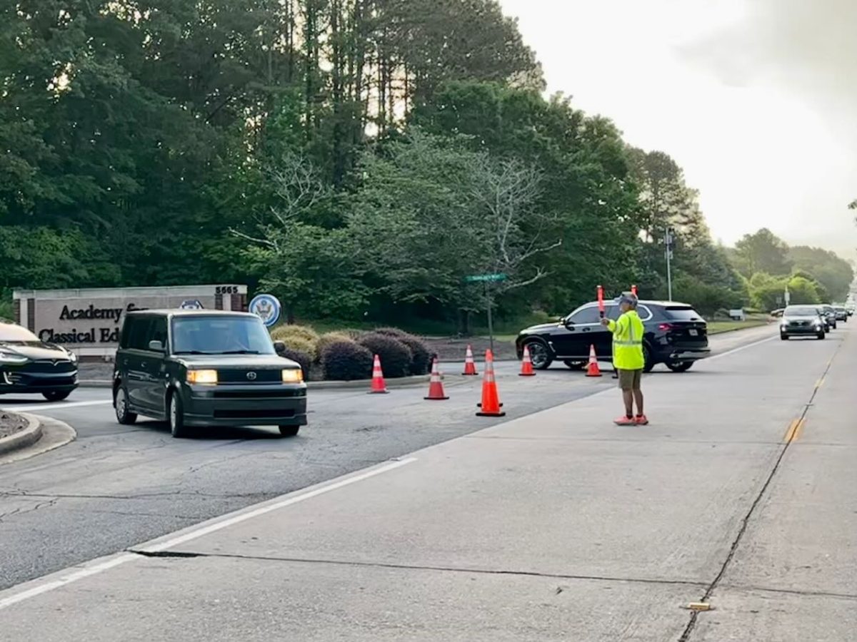 A security officer directs traffic on New Forsyth Road at the Academy for Classical Education during morning arrivals. 