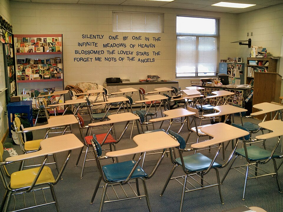 Rows of desks sit in the middle of an empty classroom 
