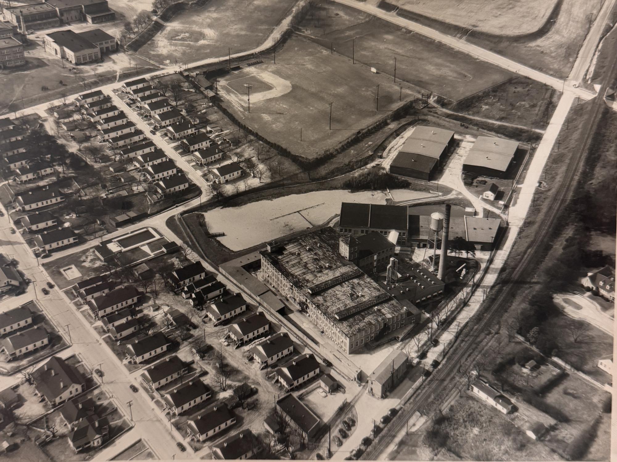 An aerial view of the Willingham Mill and surrounding mill village shows rows of worker housing, a baseball field, and the factory complex at the heart of the neighborhood. The mill’s presence shaped both the economy and daily life of its residents.