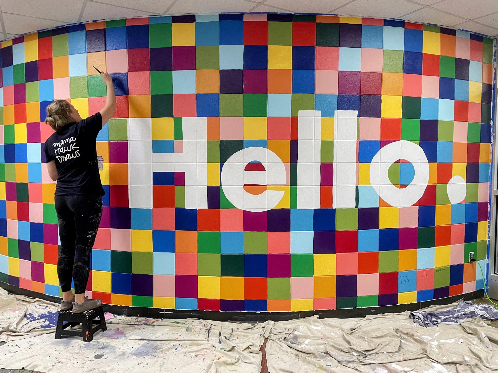 Erin Hawkins, a local muralist and studio owner that goes by “Mama Hawk Draws," is seen painting a mural piece.
