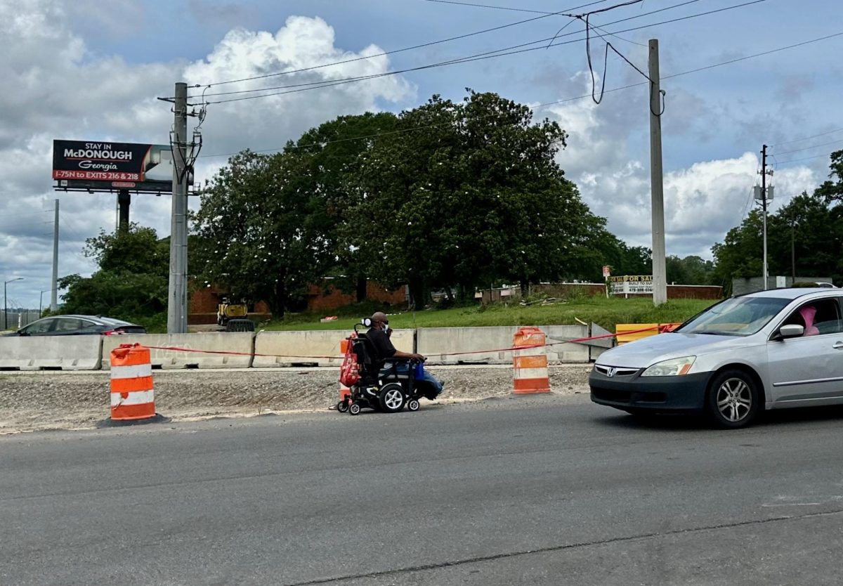 A man in a wheelchair hugs the shoulder of North Avenue while navigating the Interstate 16 West on-ramp construction zone in late June. 